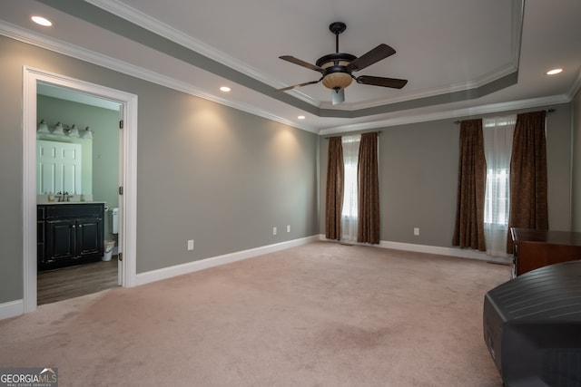 carpeted bedroom with multiple windows, a raised ceiling, connected bathroom, and crown molding