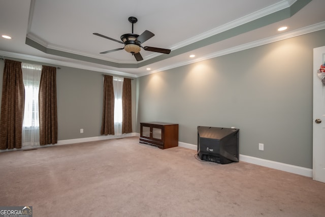 interior space with ornamental molding, a raised ceiling, light carpet, and ceiling fan