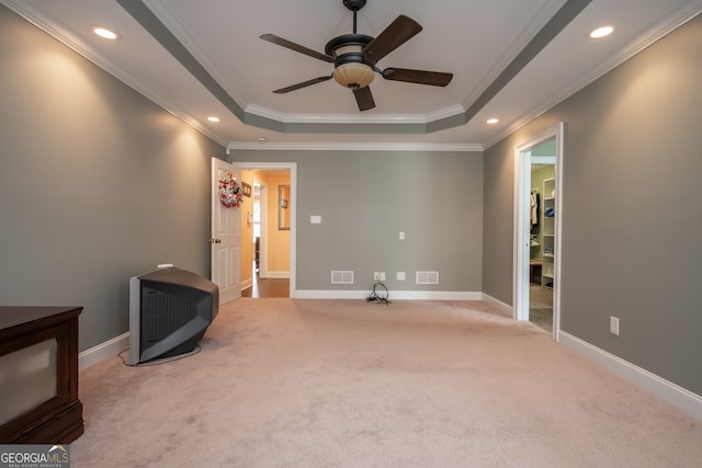 carpeted spare room featuring ceiling fan, a raised ceiling, and ornamental molding