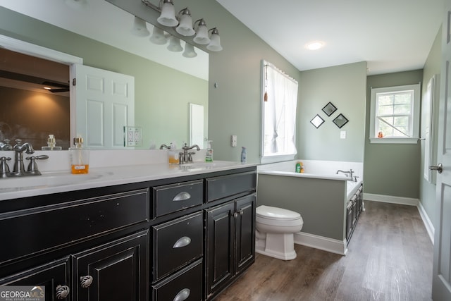 bathroom featuring vanity, toilet, hardwood / wood-style floors, and a washtub