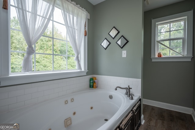 bathroom with a tub to relax in, a healthy amount of sunlight, and hardwood / wood-style flooring