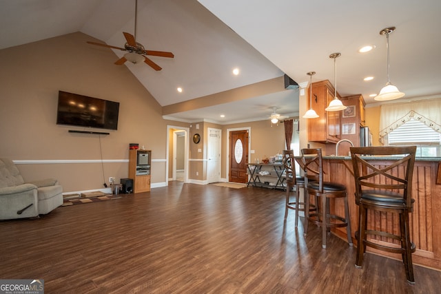 interior space featuring stainless steel refrigerator, lofted ceiling, a breakfast bar area, dark wood-type flooring, and ceiling fan