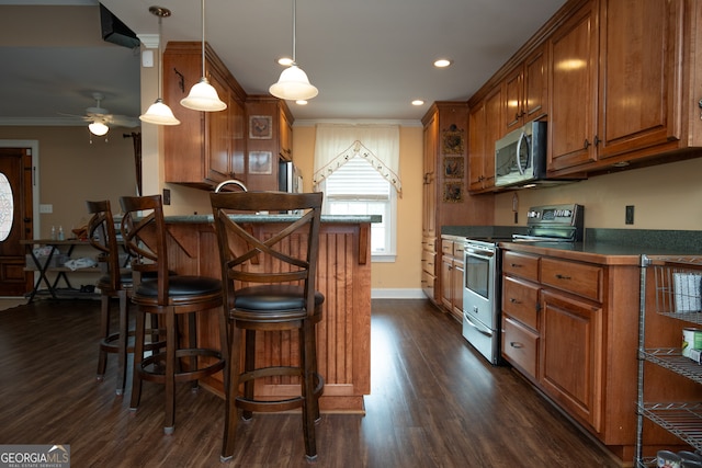 kitchen with stainless steel appliances, dark hardwood / wood-style flooring, ceiling fan, a breakfast bar area, and ornamental molding