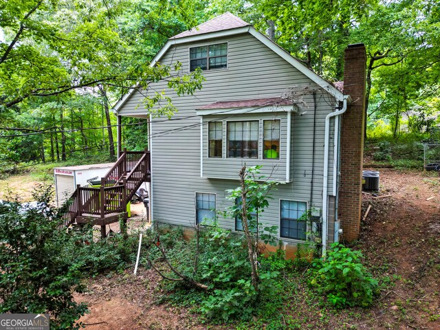 rear view of house with central AC unit and a deck