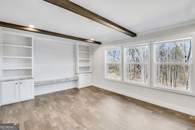 unfurnished living room featuring beam ceiling, crown molding, and hardwood / wood-style floors