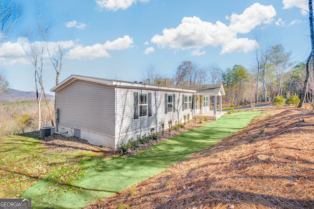 view of home's exterior featuring a porch, central AC, and a lawn