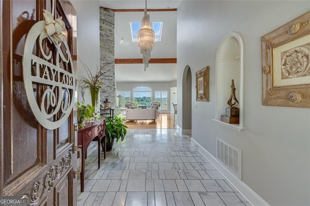 corridor featuring a high ceiling, a chandelier, and light wood-type flooring