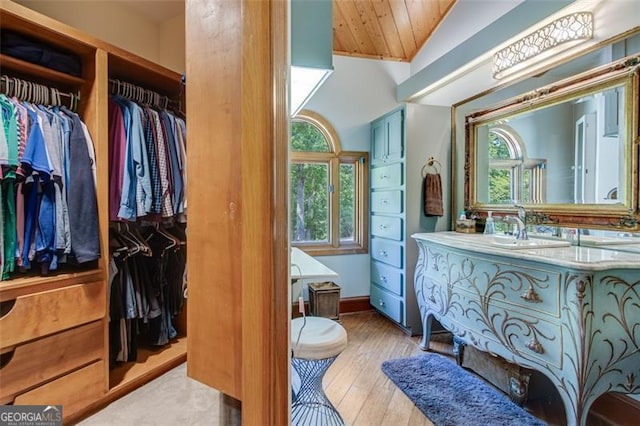 bathroom with vaulted ceiling, vanity, plenty of natural light, and wood-type flooring