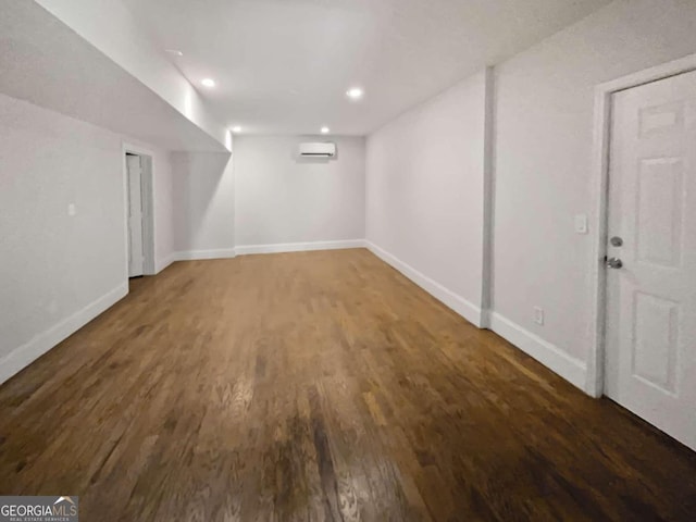 basement featuring an AC wall unit and dark hardwood / wood-style floors