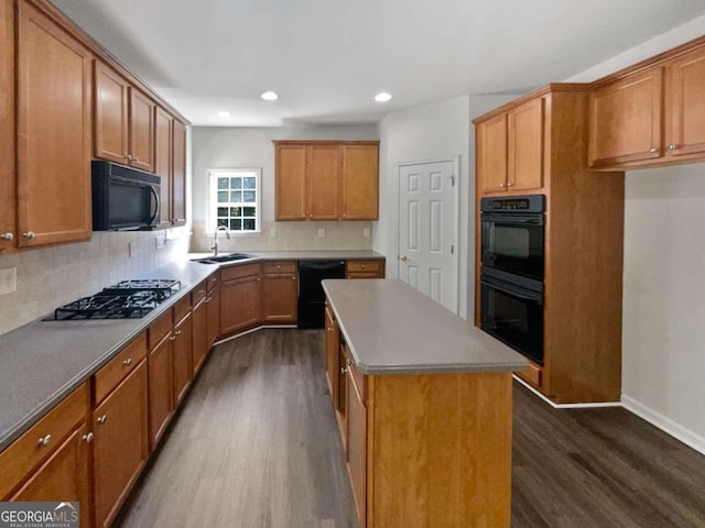 kitchen featuring dark hardwood / wood-style floors, tasteful backsplash, sink, black appliances, and a center island