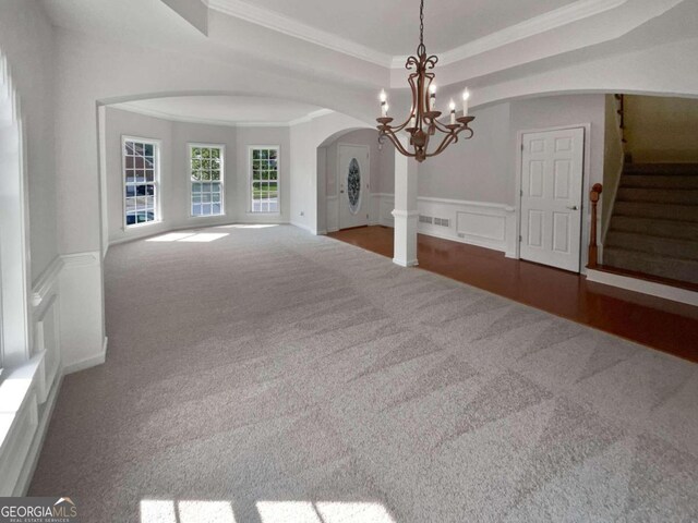 spare room with hardwood / wood-style flooring, an inviting chandelier, ornamental molding, and a tray ceiling