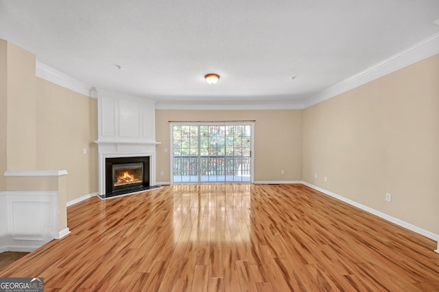 unfurnished living room with a fireplace, ornamental molding, and wood-type flooring