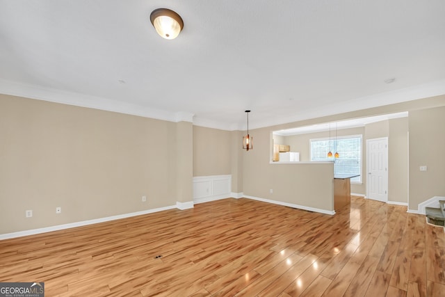 unfurnished living room featuring wood-type flooring and ornamental molding