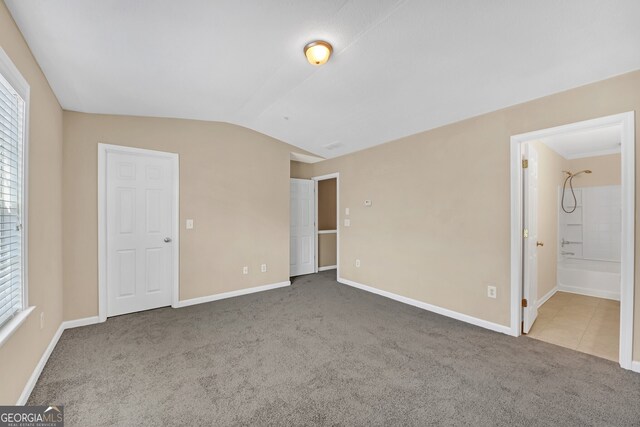 bedroom featuring lofted ceiling, carpet, and ensuite bath