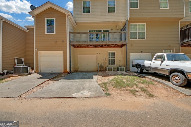 view of front of property with a balcony, central air condition unit, and a garage