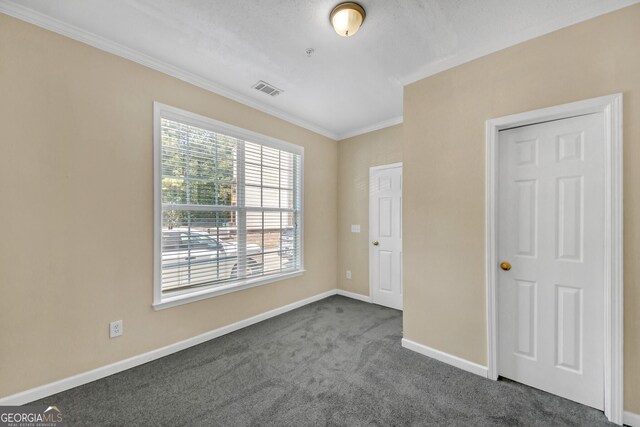 bedroom with multiple windows, dark colored carpet, and ornamental molding