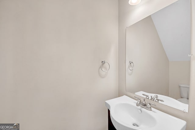 bathroom featuring toilet, sink, and vaulted ceiling