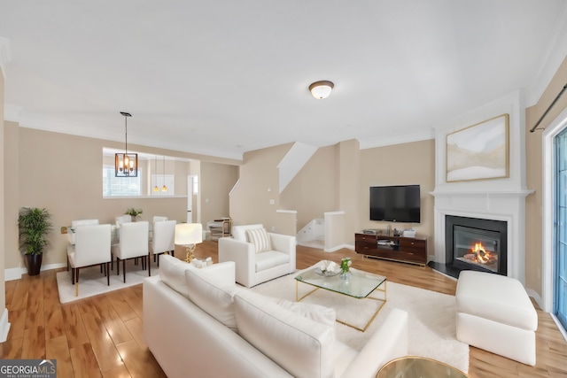 living room featuring light wood-type flooring, crown molding, and a chandelier