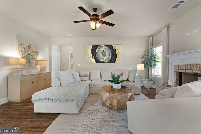 living room with ceiling fan, a fireplace, and dark wood-type flooring