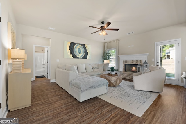 living room featuring a brick fireplace, dark hardwood / wood-style flooring, and ceiling fan