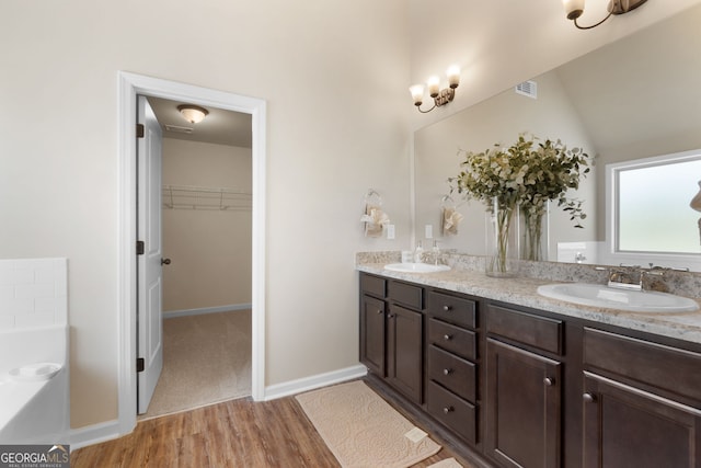 bathroom featuring vanity, lofted ceiling, hardwood / wood-style floors, and a washtub