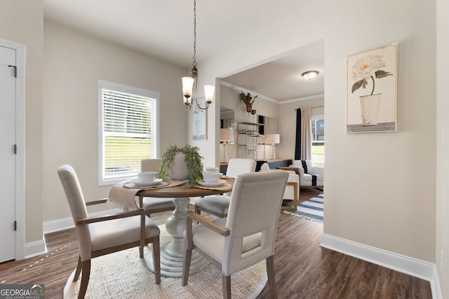 dining area with dark wood-type flooring, plenty of natural light, crown molding, and a chandelier