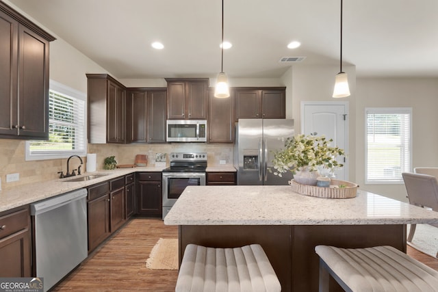 kitchen featuring stainless steel appliances, hanging light fixtures, tasteful backsplash, and sink