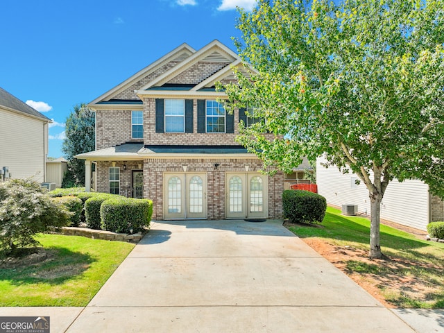 view of front of property featuring french doors, a front lawn, and central AC