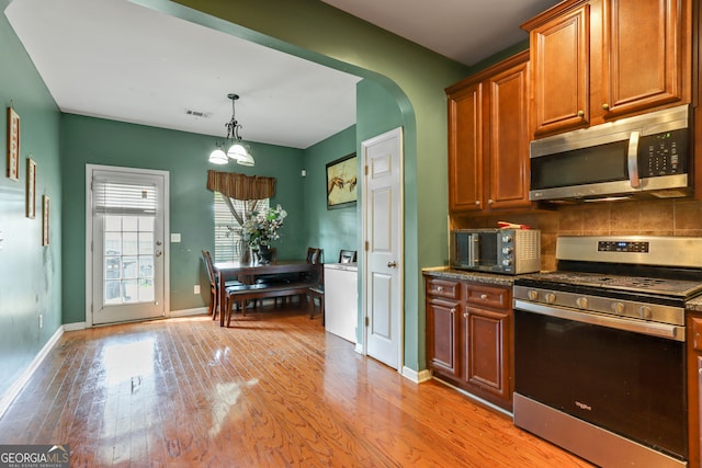 kitchen with light hardwood / wood-style flooring, appliances with stainless steel finishes, a notable chandelier, pendant lighting, and tasteful backsplash