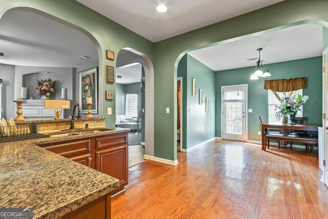 kitchen featuring light wood-type flooring, pendant lighting, an inviting chandelier, and sink