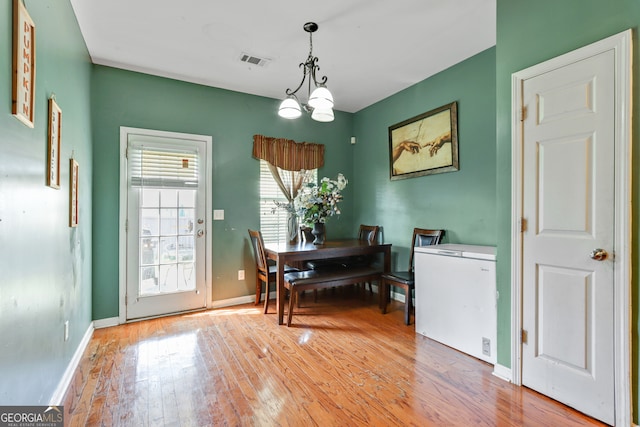 dining space with light hardwood / wood-style flooring and a chandelier