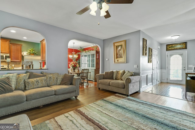 living room with ceiling fan with notable chandelier and dark hardwood / wood-style flooring