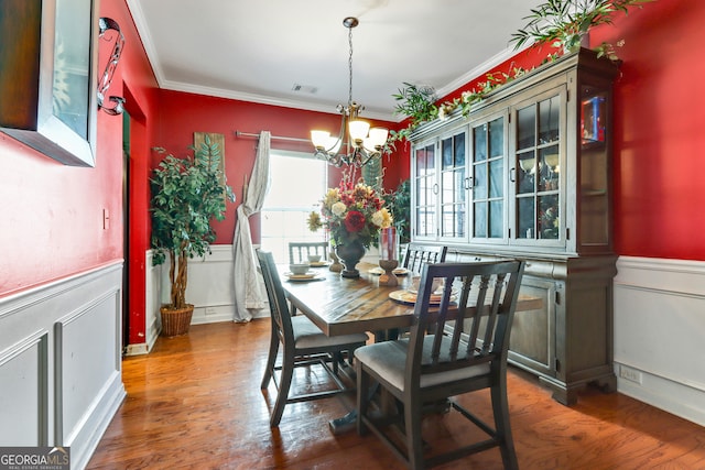 dining area with ornamental molding, a notable chandelier, and dark hardwood / wood-style flooring