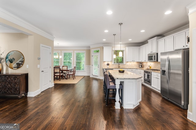 kitchen featuring appliances with stainless steel finishes, a kitchen island, decorative light fixtures, and dark hardwood / wood-style floors