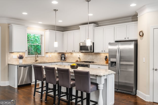 kitchen featuring appliances with stainless steel finishes, a center island, white cabinets, and hanging light fixtures