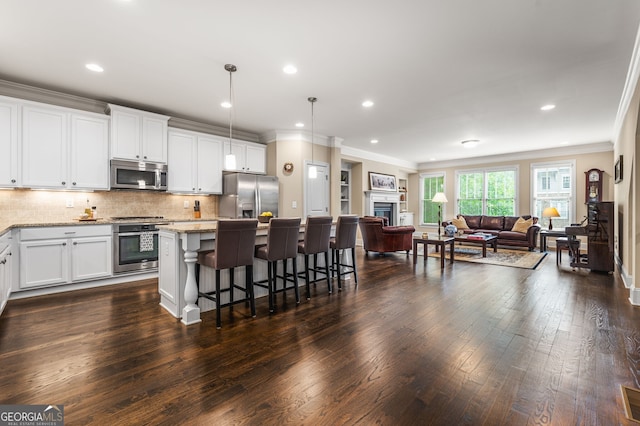 kitchen with a center island, light stone countertops, appliances with stainless steel finishes, and white cabinets