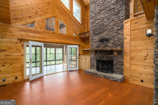 unfurnished living room with hardwood / wood-style flooring, a wealth of natural light, and a high ceiling