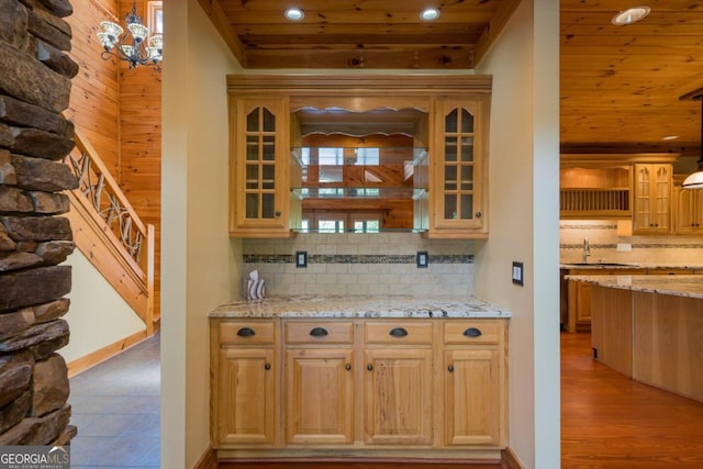 bar with decorative light fixtures, light hardwood / wood-style floors, wood ceiling, and backsplash