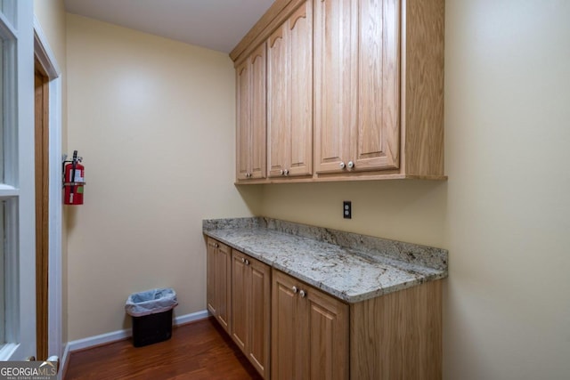 bar featuring light brown cabinetry, dark hardwood / wood-style floors, and light stone counters