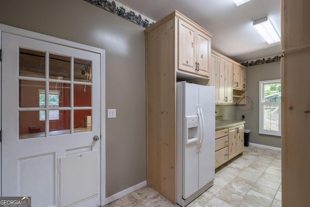 kitchen featuring white refrigerator with ice dispenser and light brown cabinetry