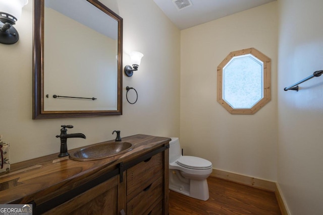 bathroom featuring toilet, vanity, and hardwood / wood-style flooring