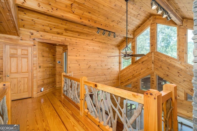 hall featuring wooden ceiling, wood-type flooring, vaulted ceiling, track lighting, and wooden walls