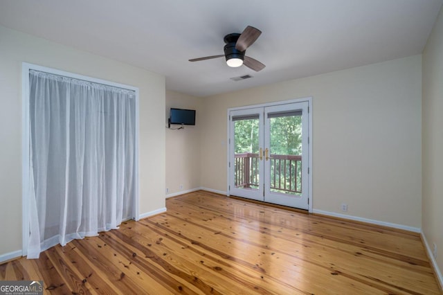 empty room with french doors, light wood-type flooring, and ceiling fan