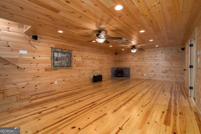 unfurnished living room featuring light hardwood / wood-style floors, wooden ceiling, and wooden walls