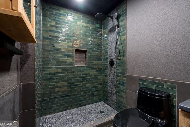 bathroom with toilet, tile walls, and tiled shower