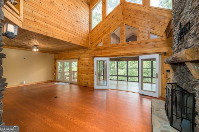 unfurnished living room with a fireplace, a towering ceiling, hardwood / wood-style flooring, and wooden ceiling