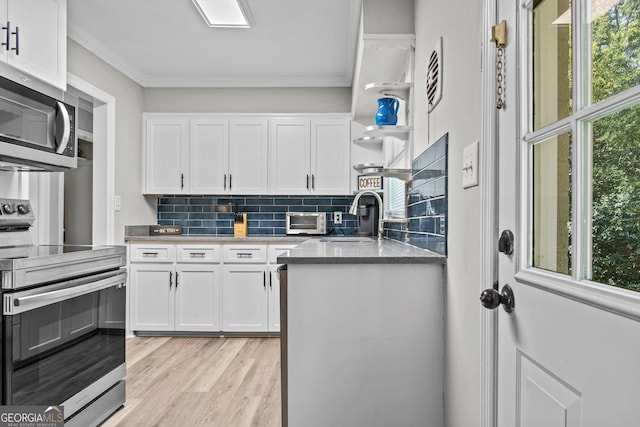 kitchen featuring open shelves, stainless steel appliances, ornamental molding, white cabinetry, and a sink