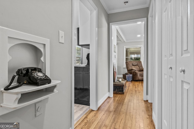 hallway with light wood finished floors, baseboards, and ornamental molding