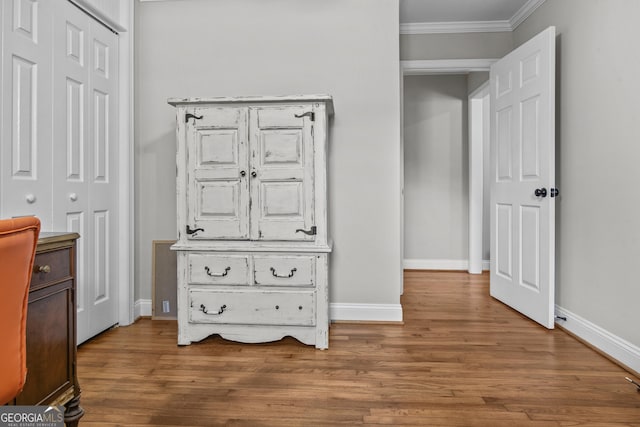 interior space with baseboards, a closet, ornamental molding, and wood finished floors