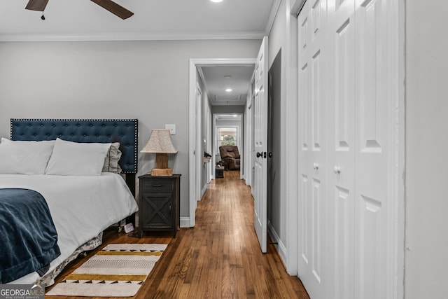 bedroom with a closet, crown molding, baseboards, and wood finished floors